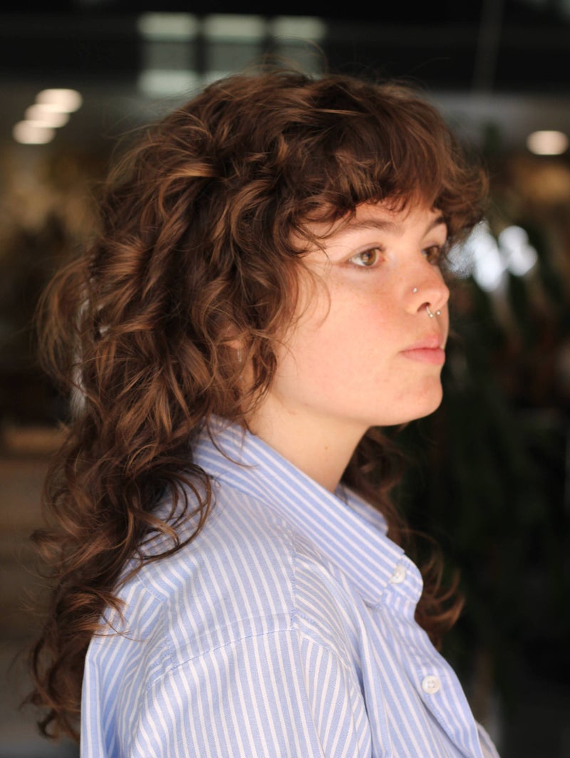 Client with a curly shag haircut and bangs by Hope